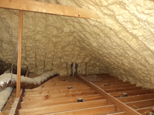 Spray foam insulation being applied in a residential attic, highlighting potential risks and benefits.