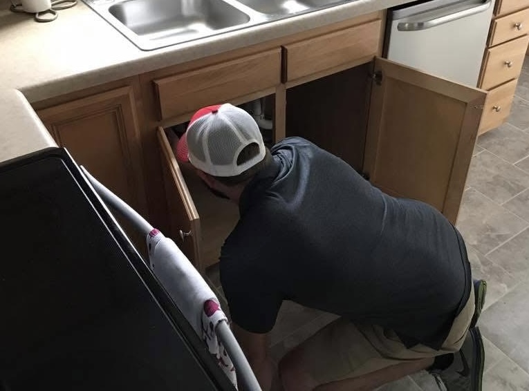 Certified home inspector examining kitchen plumbing during a home inspection in Winston-Salem NC.